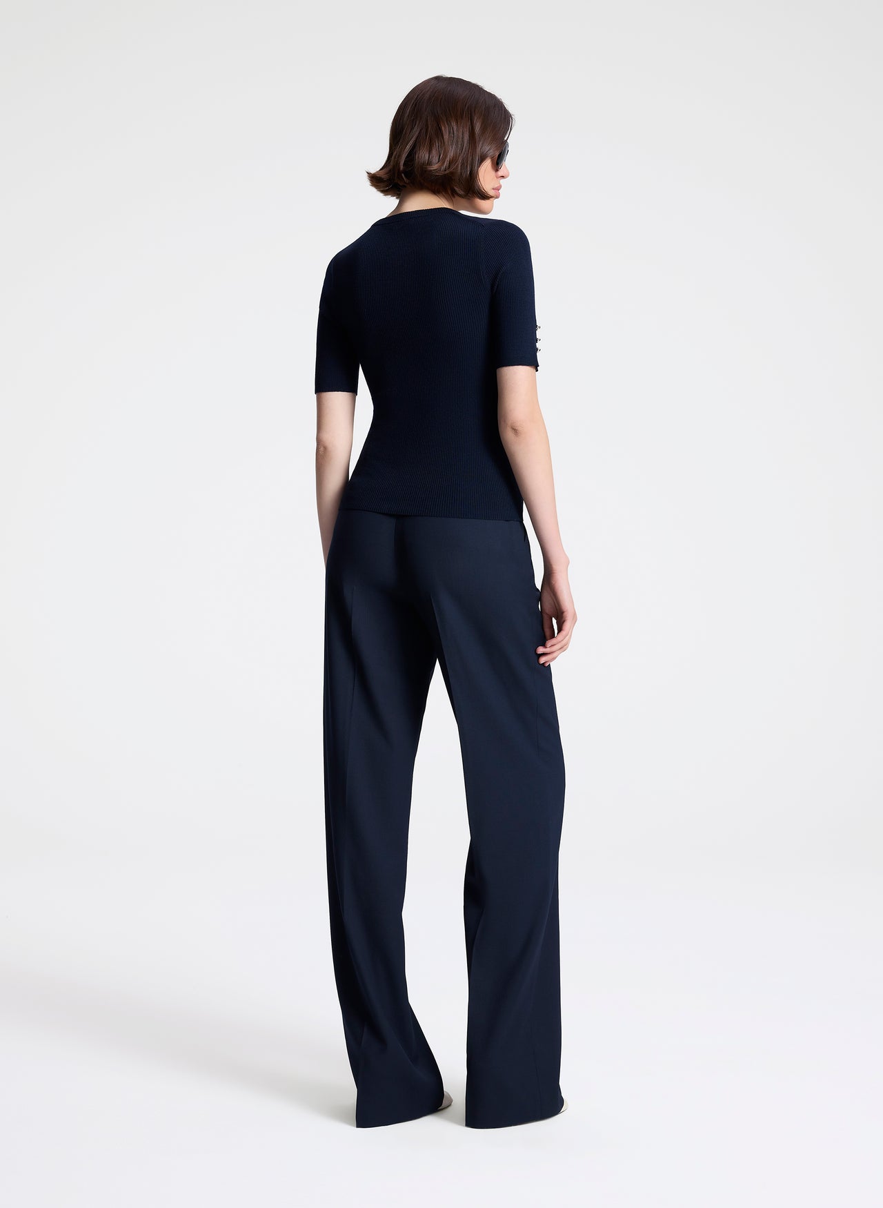 Person wearing a navy outfit with a top and wide-leg pants on a white background