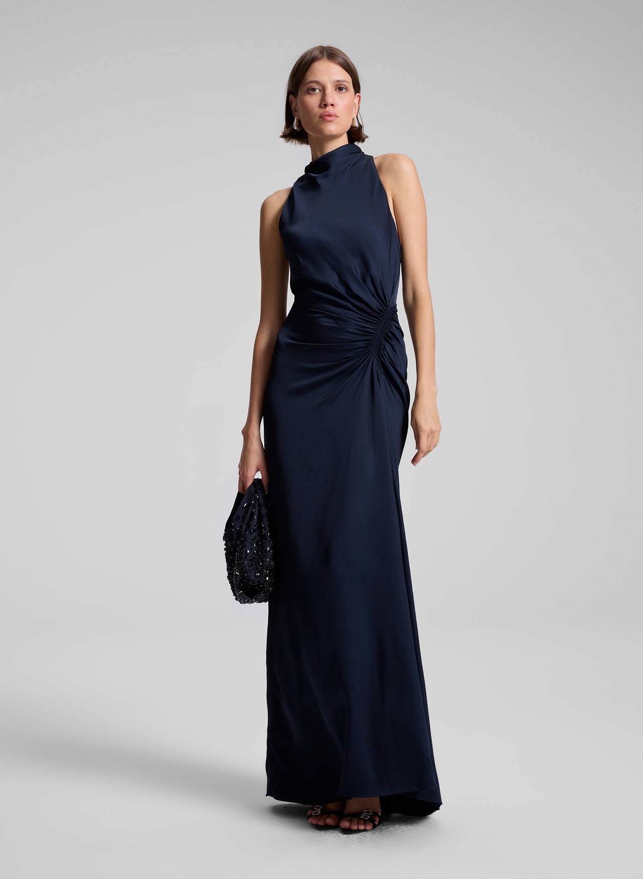 Woman wearing a navy blue evening gown on a gray background