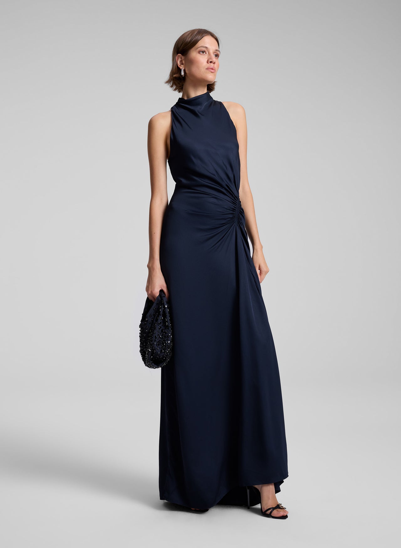 Woman wearing a navy blue evening gown on a light gray background