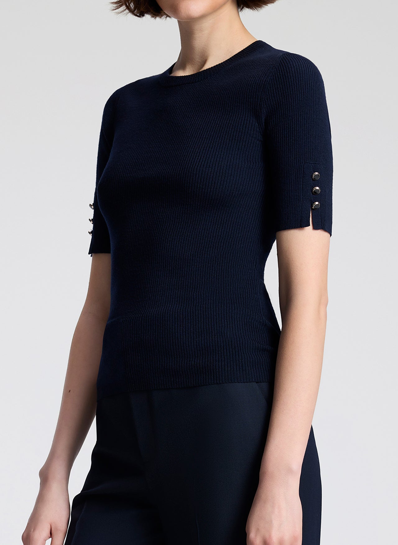 Navy blue short-sleeve top with decorative buttons on a plain background